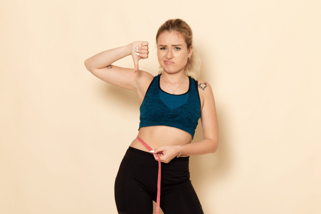 Testosterone for Women Weight Loss | Boost Fat Burn, Energy & Confidence in NYC Front View Young Female Sport Outfit Measuring Her Body 1 Scaled 1 1024x683